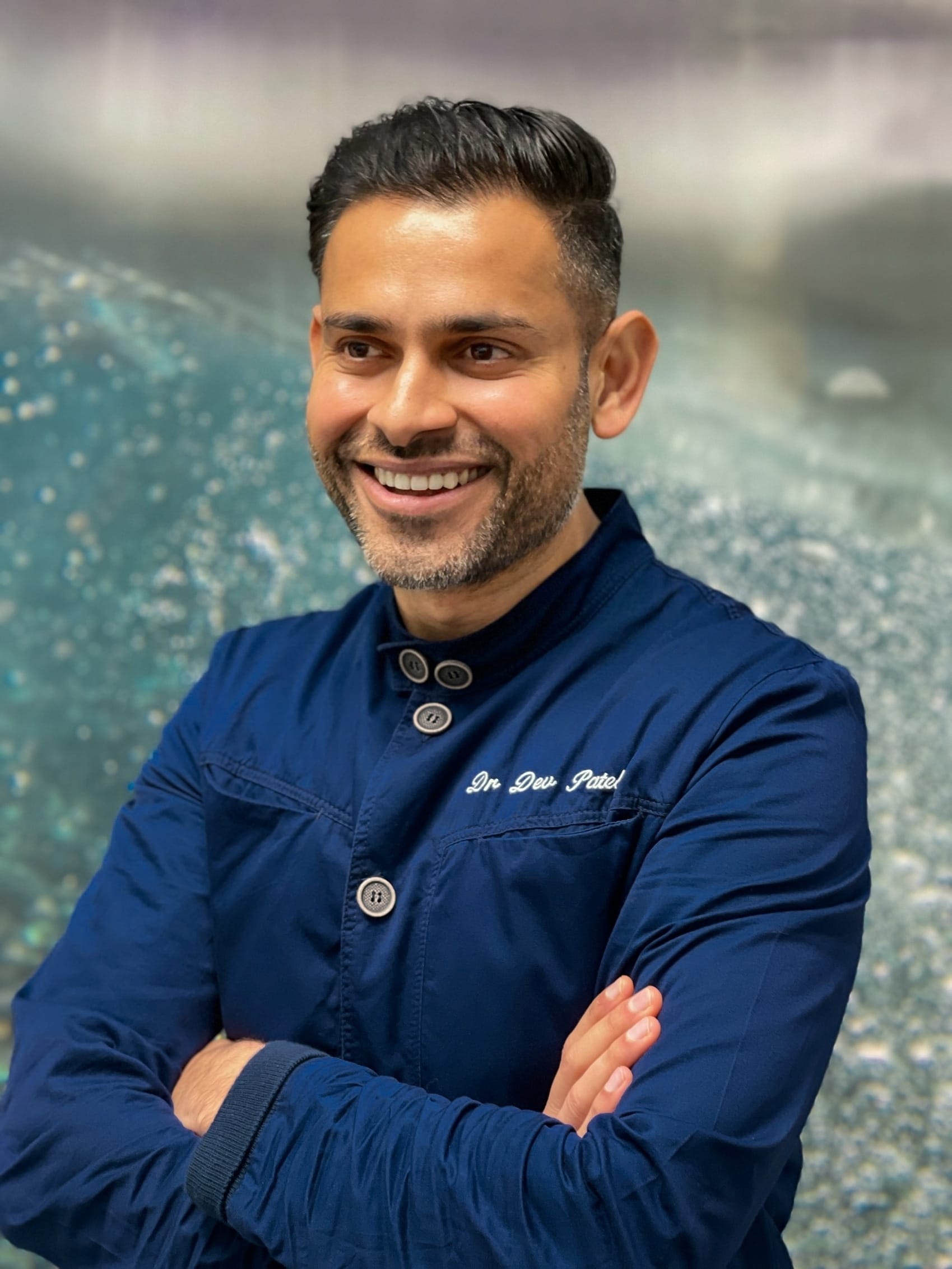 Dev Patel headshot in blue scrubs