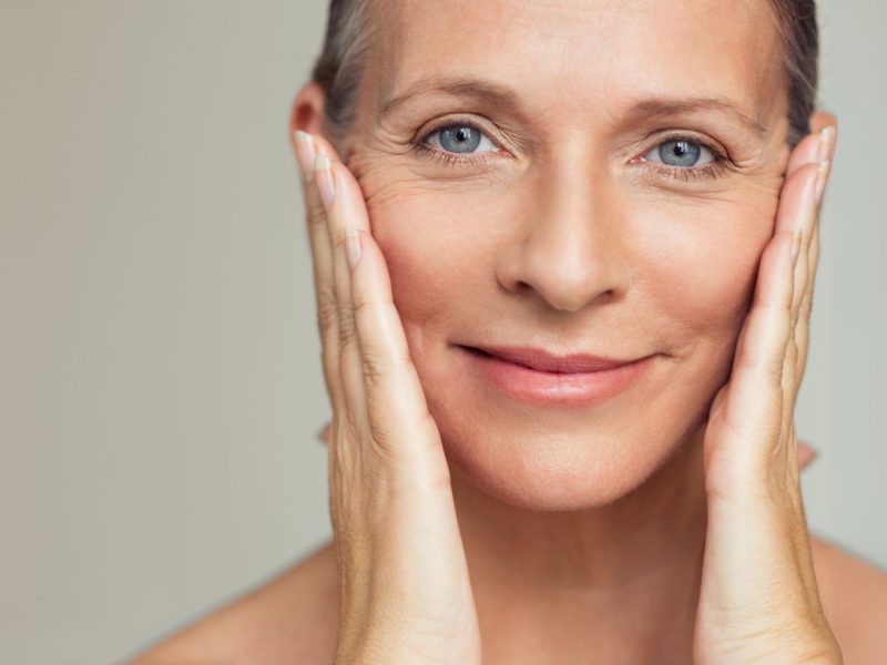 mature lady women with clear skin hands touching face menopause