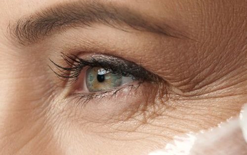 close up of womens eye applying cream showcasing premature ageing eye wrinkles