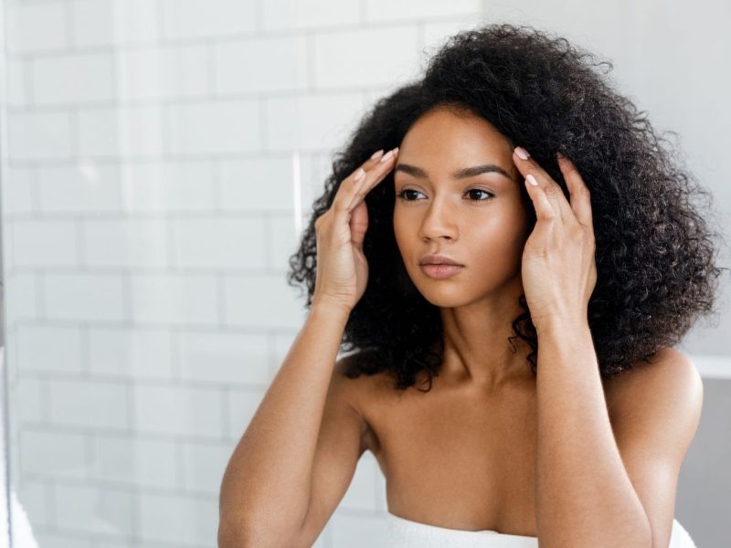 woman looking in mirror looking sad stress touching face