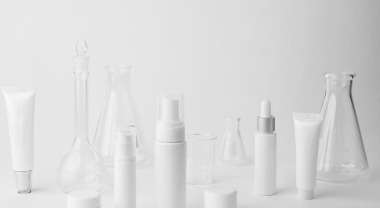 many unbranded skincare bottles on a grey studio floor background