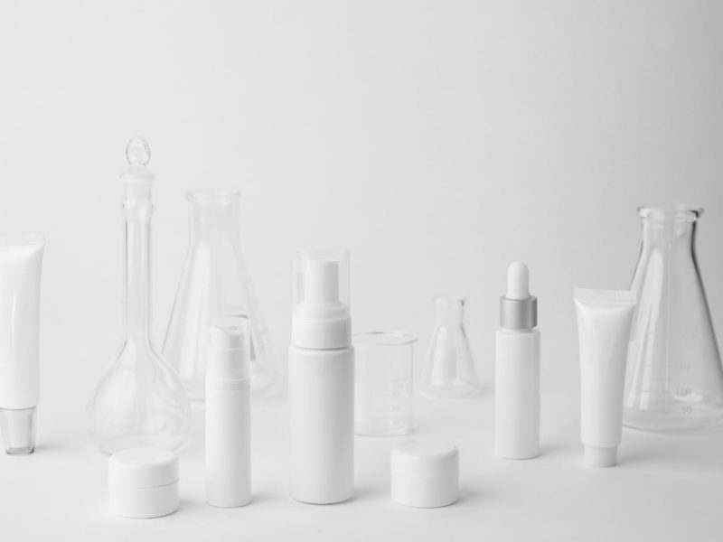 many unbranded skincare bottles on a grey studio floor background